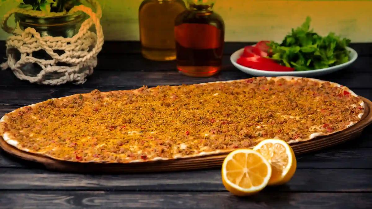 Lahmacun with lemon Thin round lahmacun topped with minced meat, served with lemon halves and parsley