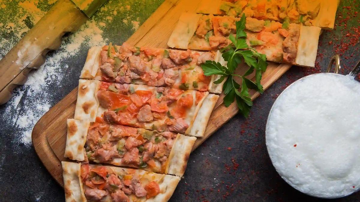 Pide with spiced sausage and cheese Pide topped with spiced cured sausage and cheese, served with a glass of ayran